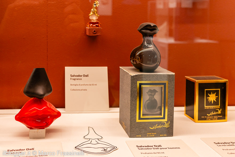 Esposizione in vetrina di flaconi di profumo surrealisti ispirati a Salvador Dalí, tra cui uno celebre a forma di labbra rosse sormontate da un naso nero e confezioni firmate dall'artista